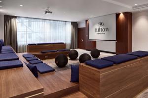 维也纳Hilton Vienna Park的一间会议室,配有蓝色椅子和投影屏幕