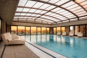 马德里希尔顿马德里机场酒店的一个带椅子和天花板的大型室内游泳池