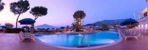 索伦托希尔顿索伦托皇宫酒店的度假村内的大型游泳池配有椅子和遮阳伞