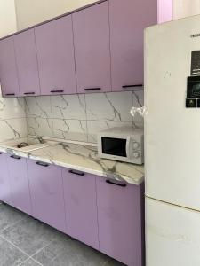 阿拉木图Tastaq hostel的厨房配有紫色橱柜和白色冰箱