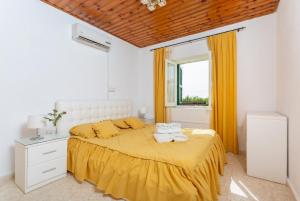 Kato YialiaAndroula Villas Collection的一间卧室配有一张带黄色床单的床和一扇窗户。