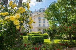 凡尔赛Waldorf Astoria Versailles - Trianon Palace的院子里的白色大房子,花黄色