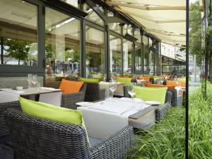 安特卫普安特卫普老城希尔顿酒店的餐厅设有白色的桌椅和窗户。