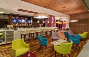 华沙华沙市中心希尔顿汉普顿酒店的一间设有五颜六色椅子的餐厅和一间酒吧