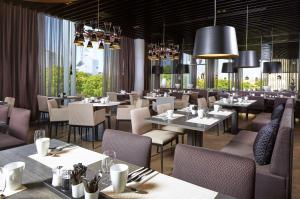 塔林希尔顿塔林公园酒店的用餐室配有桌椅和吊灯。