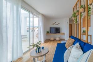 圣米格尔德阿沃纳Ático Cholas by the Beach的客厅设有蓝色的沙发和大窗户