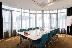 霍夫多普阿姆斯特丹史基浦机场希尔顿恒庭酒店的一间会议室,配有白色的桌子和椅子