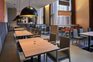 柏林柏林市中心亚历山大广场希尔顿汉普顿酒店的餐厅设有木桌、椅子和窗户。