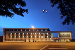 奥托佩尼Hilton Garden Inn Bucharest Airport的飞机在医院的大楼上空飞行