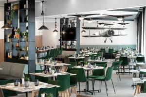 奥托佩尼Hilton Garden Inn Bucharest Airport的用餐室配有桌子和绿色椅子