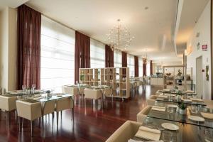 佛罗伦萨希尔顿佛罗伦萨大都市酒店的餐厅设有白色的桌椅和大窗户