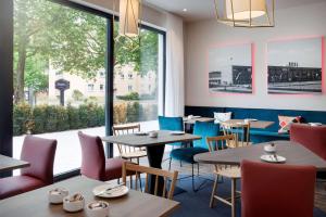 凯撒斯劳滕Hampton By Hilton Kaiserslautern的餐厅设有桌椅和大窗户。