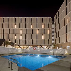 阿尔考本达斯Hampton By Hilton Alcobendas Madrid的一座游泳池,在晚上在建筑物前