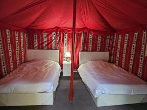 Al-DisahMango Farm Camp的红色帐篷间内的两张床