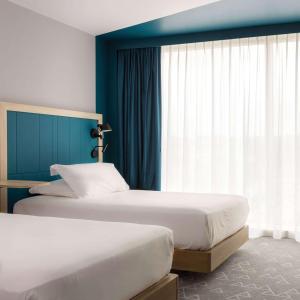 图尔Hampton by Hilton Tours Centre, France的配有两张床铺的蓝色墙壁和窗户