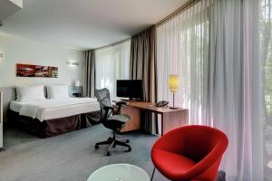 斯图加特斯图加特希尔顿酒店耐卡公园店的酒店客房,配有一张床和一张红色椅子
