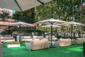 巴塞罗那希尔顿巴塞罗那酒店的庭院设有白色的椅子和遮阳伞,位于草地上