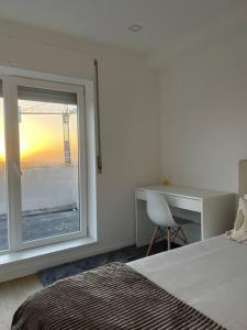波尔图Quarto duplo com casa de banho exclusiva no Porto的一间卧室配有一张床、一张书桌和一个窗户。