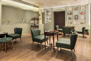里斯本The Emerald House Lisbon - Curio Collection By Hilton的一间设有绿色椅子和桌子的等候室