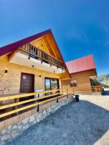 佩奇Hotel Te Liqeni的大型木制小屋,设有红色屋顶