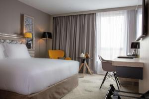 马西Hilton Garden Inn Paris Massy的酒店客房设有一张白色大床和一张书桌