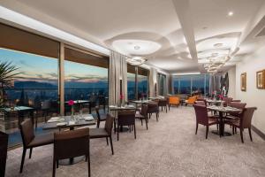 波德戈里察科纳格拉酒店的餐厅设有桌椅和大窗户。
