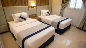 塔伊夫نسيم الشفا للشقق الفندقية的酒店客房带两张床,带白色和蓝色的床单