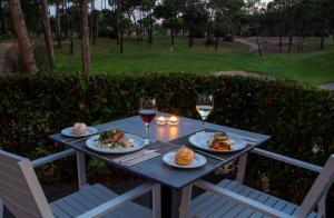 伊斯兰蒂拉DoubleTree by Hilton Islantilla Beach Golf Resort的餐桌,带食物盘和两杯葡萄酒