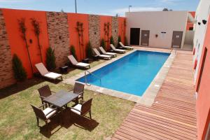 阿瓜斯卡连特斯Hampton Inn & Suites by Hilton Aguascalientes Aeropuerto的一座带椅子和桌子的游泳池位于大楼旁