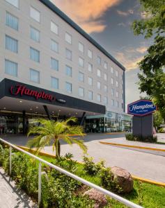 阿瓜斯卡连特斯Hampton by Hilton Aguascalientes Downtown的一座酒店大楼,前面有棕榈树