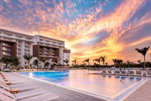 棕榈滩Embassy Suites By Hilton Aruba Beach Resort的度假村的游泳池,配有椅子和日落