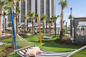 默特尔比奇Embassy Suites by Hilton Myrtle Beach Oceanfront Resort的棕榈树公园和建筑中的吊床