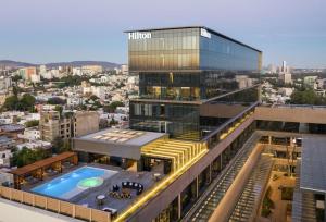 瓜达拉哈拉Hilton Guadalajara Midtown的城市前方带游泳池的建筑