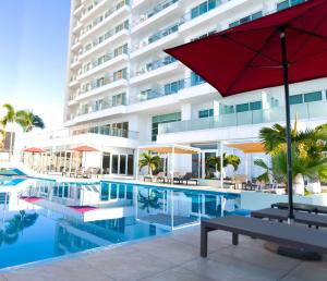 马萨特兰DoubleTree by Hilton Mazatlan, SIN的一个带红伞的游泳池和一座建筑
