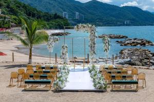 巴亚尔塔港Hilton Vallarta Riviera All-Inclusive Resort,Puerto Vallarta的海滩上婚礼仪式的布置,椅子