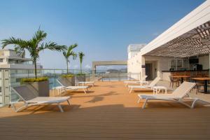 圣玛尔塔Hilton Garden Inn Santa Marta的一个带白色椅子和桌子的甲板,棕榈树