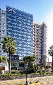 利马Hilton Garden Inn Lima Miraflores的一座高大的建筑,前面有棕榈树