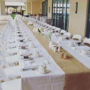 布里奇敦希尔顿巴巴多斯度假酒店 的一张长桌子,上面有白色的桌子和白色的椅子