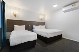 皇后镇Lakeview Colonial Motel的配有白色床单的酒店客房内的两张床
