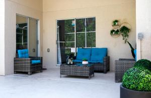 基西米Private house Kissimmee/Orlando的庭院设有藤椅和带蓝色座椅的桌子。