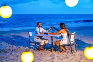 后川PLAYA Villa in Sanctuary Resort - 100m from Private Beach - New 2023的坐在海滩桌子上的男人和女人