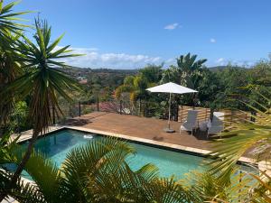 黄金海岸Gold Coast uninterrupted uphill view & big pool的一个带两把椅子和遮阳伞的游泳池