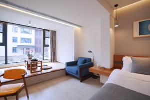 青岛青岛九水和园艺术设计酒店的卧室配有床、椅子和窗户。
