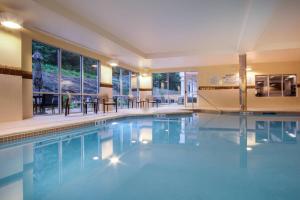 莱诺克斯Courtyard by Marriott Lenox Berkshires的酒店设有带桌椅的游泳池