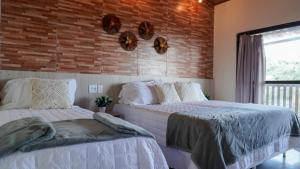 贝泽罗斯POUSADA KALUKA的卧室设有2张床,设有砖墙
