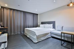 昌原市The First Hotel的卧室配有一张白色的大床和一张沙发。