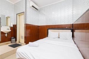 当格浪Alfa Guesthouse Serpong Mitra RedDoorz的卧室配有白色的床和水槽