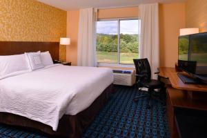 普利茅斯Fairfield Inn & Suites by Marriott Plymouth White Mountains的配有一张床、一张书桌和一扇窗户的酒店客房