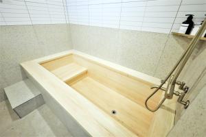 统营市De Lamour Hotel的浴室铺有木地板,配有浴缸。