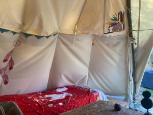 Tourrette-LevensTipis La Paix retrouvée的帐篷前设有红色的床
